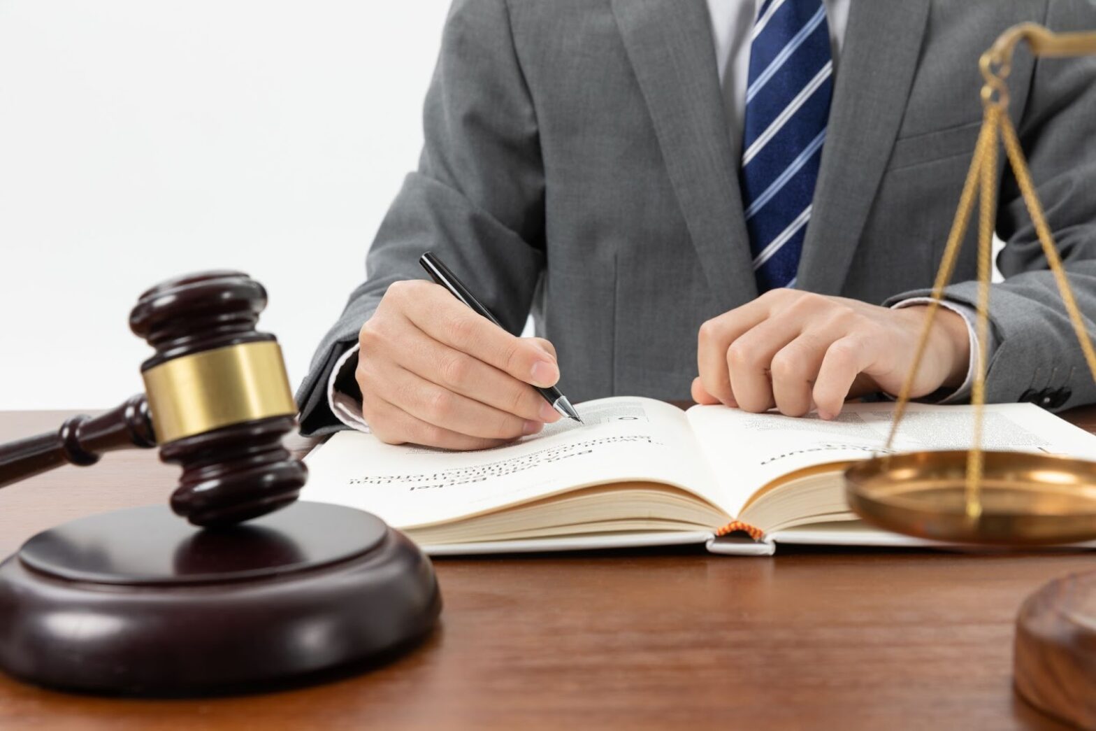 Close up shot of a person writing in a book with a gavel on the table
