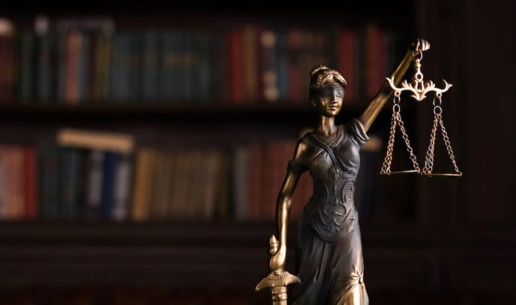 Statue of Lady Justice in front of a bookshelf