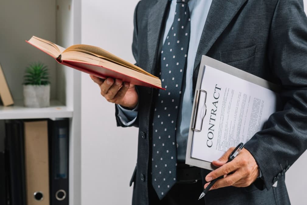 A professional holding a book and a contract folder, ready for review