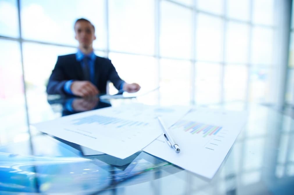 Blurred image of a businessman at a desk with graphs