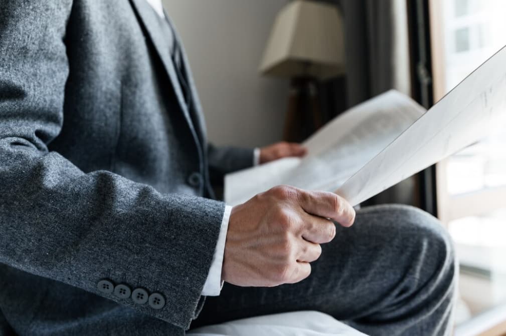 Close-up of a man reading documents in a gray suit