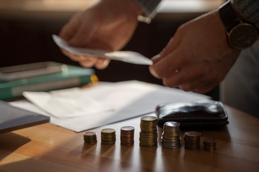 A person counts coins and examines bills with a wallet nearby