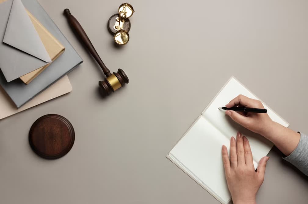 Top view of a hand writing beside a gavel and scales