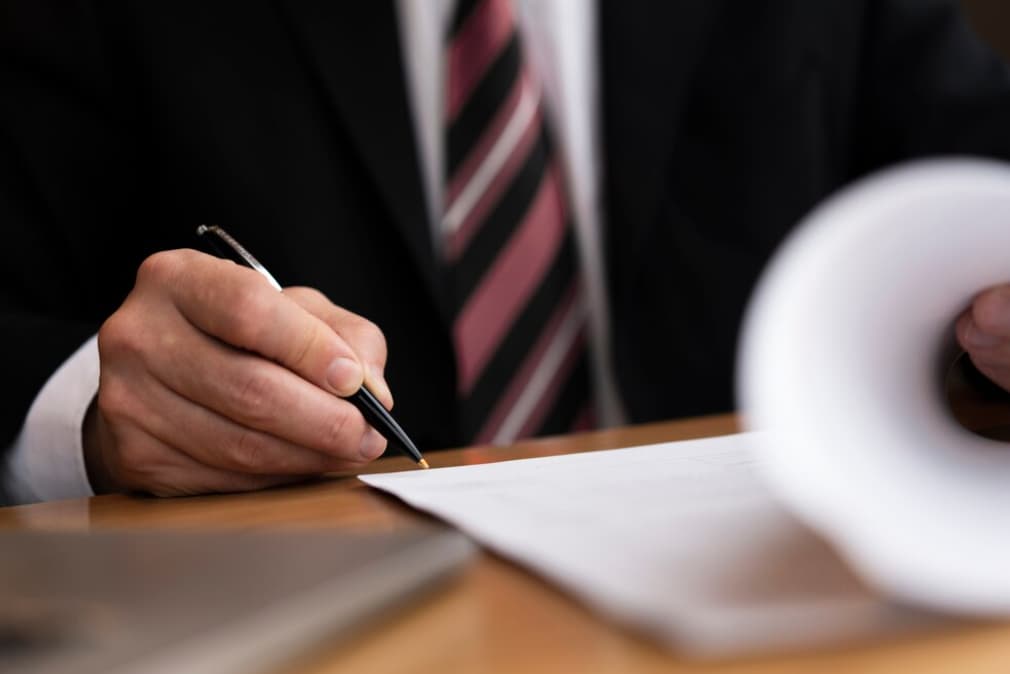 Close-up of a man's hands writing on paper at a desk